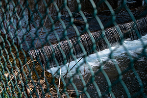 a waterfall seen through a wired fence