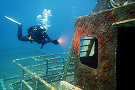 A diver uses a light to explore a shipwreck