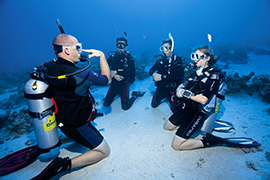 A group of four divers practice breathing underwater