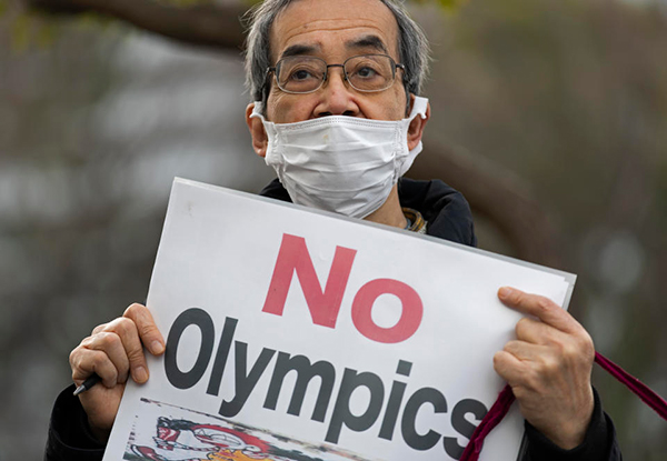 A Protester holding up a sign saying 'NO OLYMPICS'