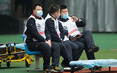 A Few athletes sit on a bench wearing covid masks