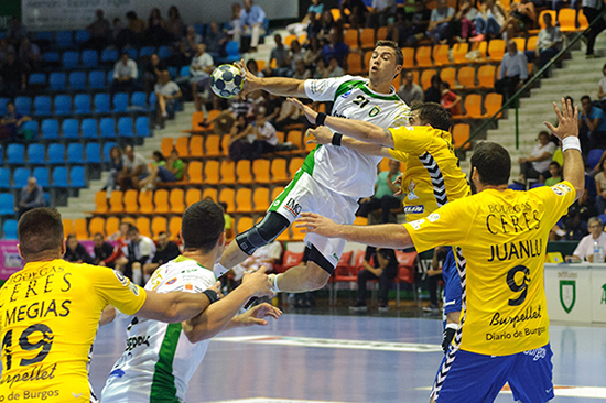 A Handball player is tackled mid-air with the ball in hand