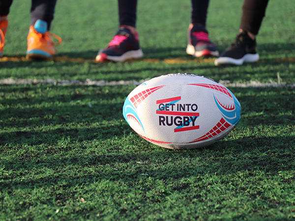 A close-up of a Rugby ball with 'get into rugby' written on it.