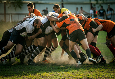 Two teams of rugby players clash on the field.