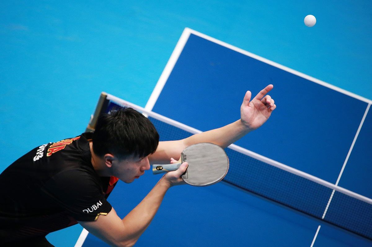 A Top-down photo of a ping-pong player observing the ball in motion.