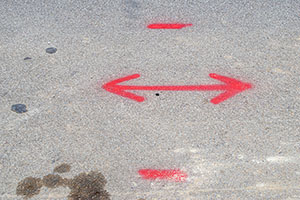 A distinct red arrow seen on a dull grey road