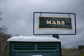 A sign reading MARS above an outhouse.