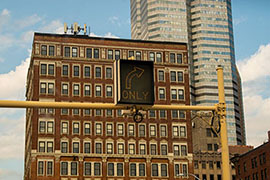 A Turn-left signal with buildings in the background