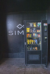 A Vending machine in front of a SIM sign.